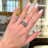 Sapphire and diamond checkerboard ring worn on hand.