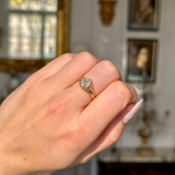Antique solitaire diamond engagement ring worn on closed hand.