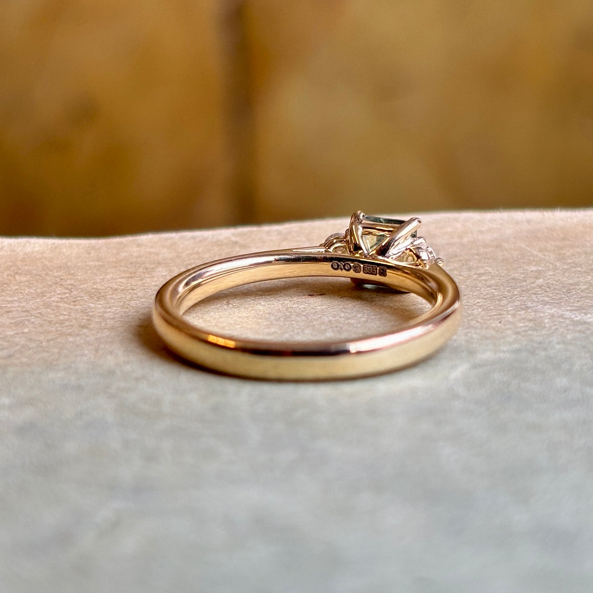 Hallmarks of Square-cut teal sapphire and diamond three-stone engagement ring.