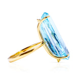 Large aquamarine and yellow gold cocktail ring on a white background, side of ring perspective. 