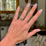 Three stone emerald-cut diamond ring, worn on left hand, ring finger. Shot with antiquated bokeh background