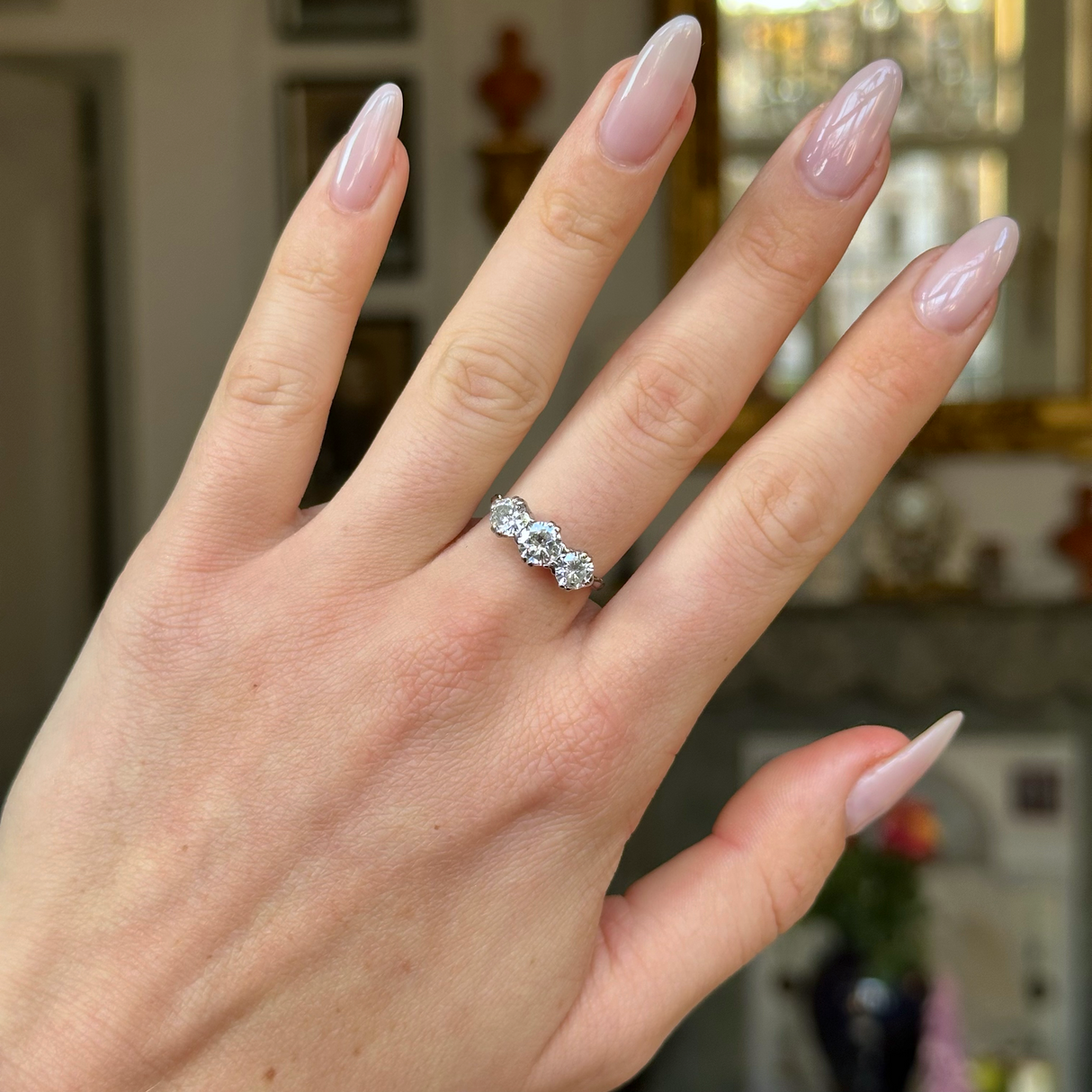 Vintage three stone diamond engagement ring worn on hand. 