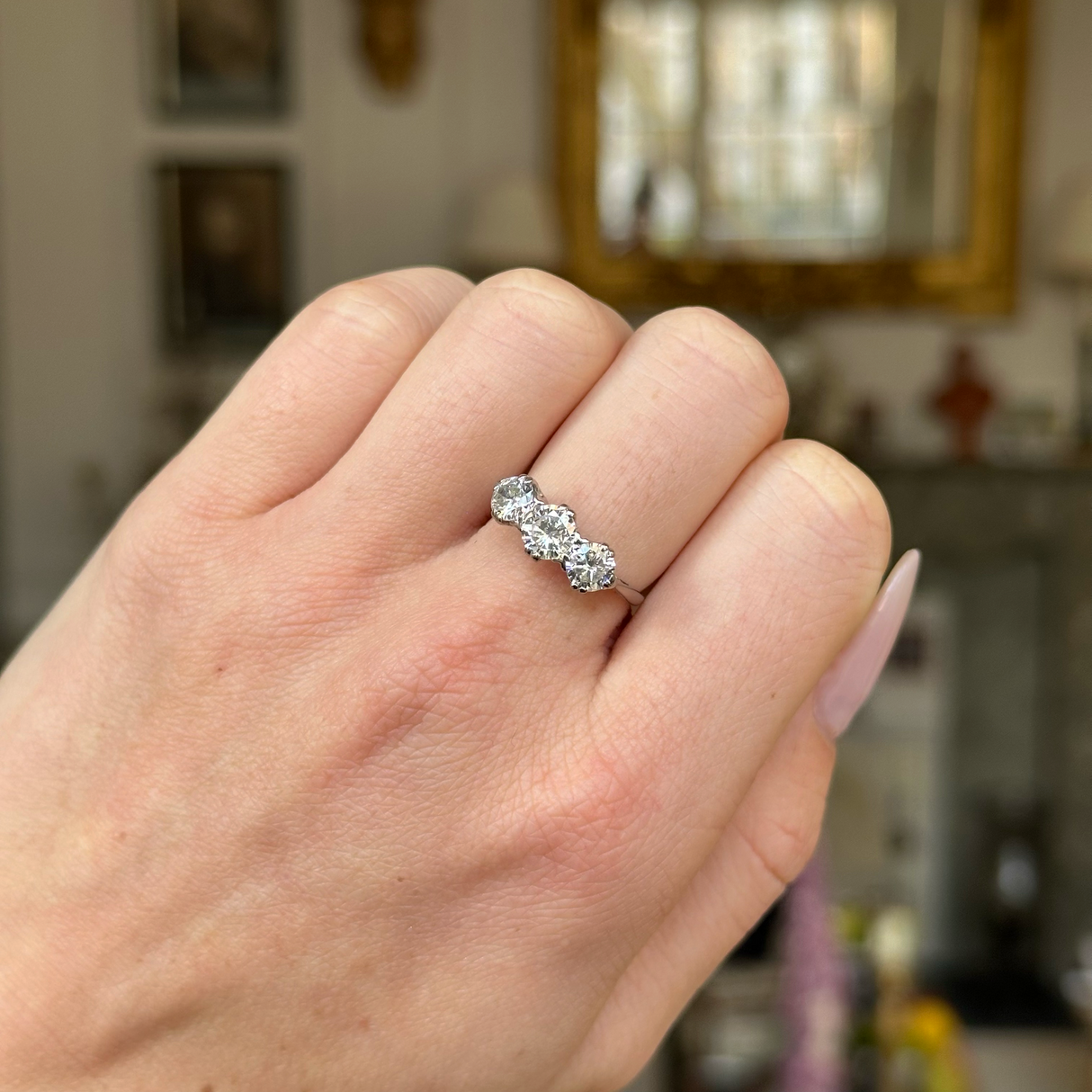 Vintage three stone diamond engagement ring worn on closed hand. 