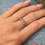 three stone diamond engagement ring, worn on hand placed on jeans, front view.