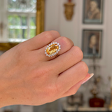 Imperial topaz and diamond cluster ring with gold band on closed hand
