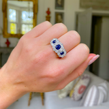 Antique sapphire and diamond triple cluster ring worn on hand.