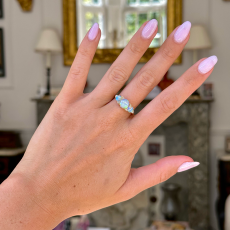 Opal and diamond three stone ring worn on hand, front view. 