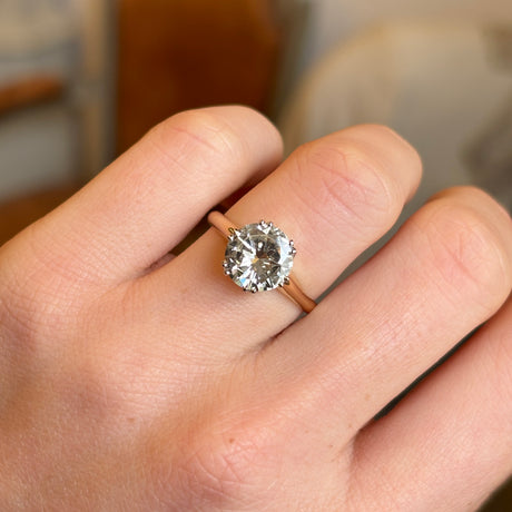 A vintage 1950s, diamond solitaire ring worn on a hand captured close up. 