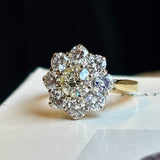 Vintage 1980s diamond cluster ring captured to show the diamonds colour, placed on a vintage book at a 45 degree angle to show proportions. 