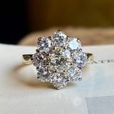 Vintage 1980s diamond cluster ring captured to show the diamonds colour, placed on a vintage book to show proportions. 