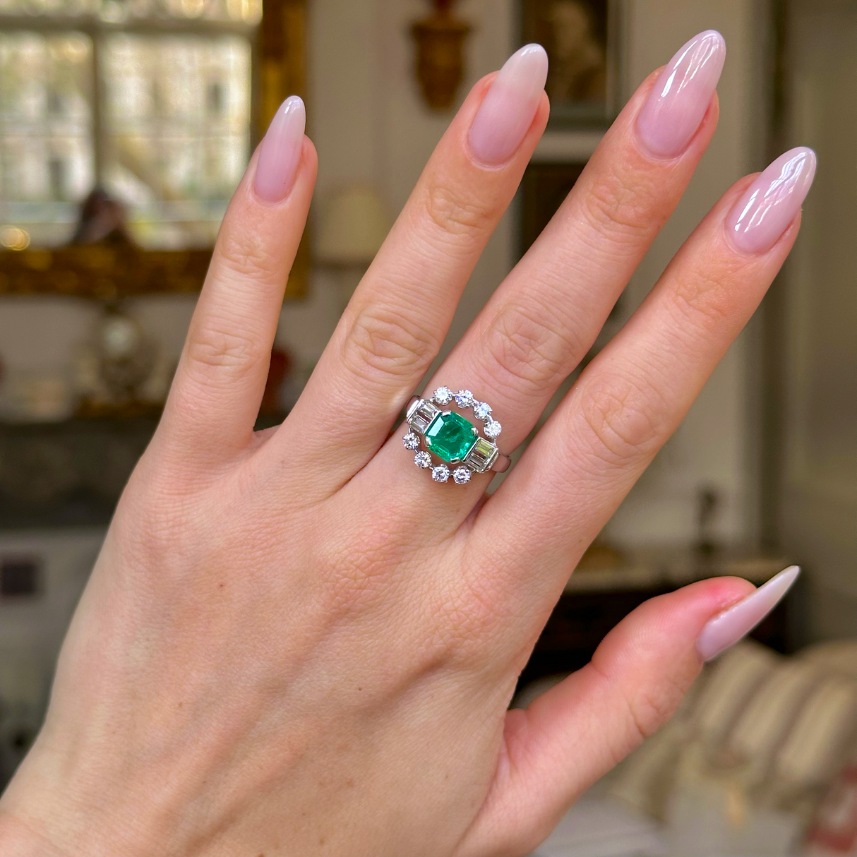 Vintage emerald and diamond ring worn on hand. 