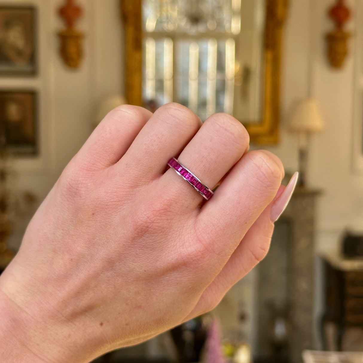 Vintage ruby eternity ring worn on closed hand.