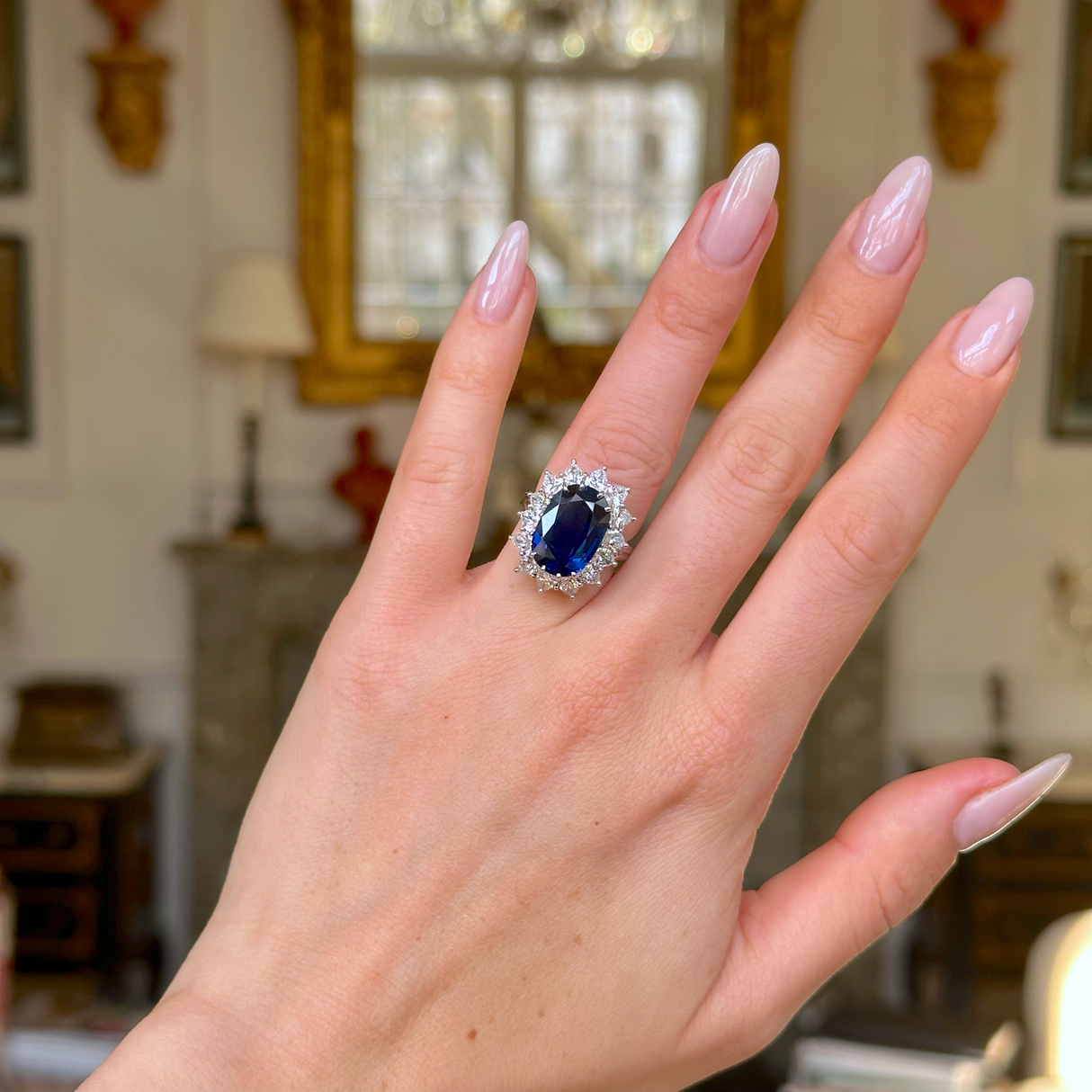 A vintage sapphire and diamond cluster ring worn on hand. 