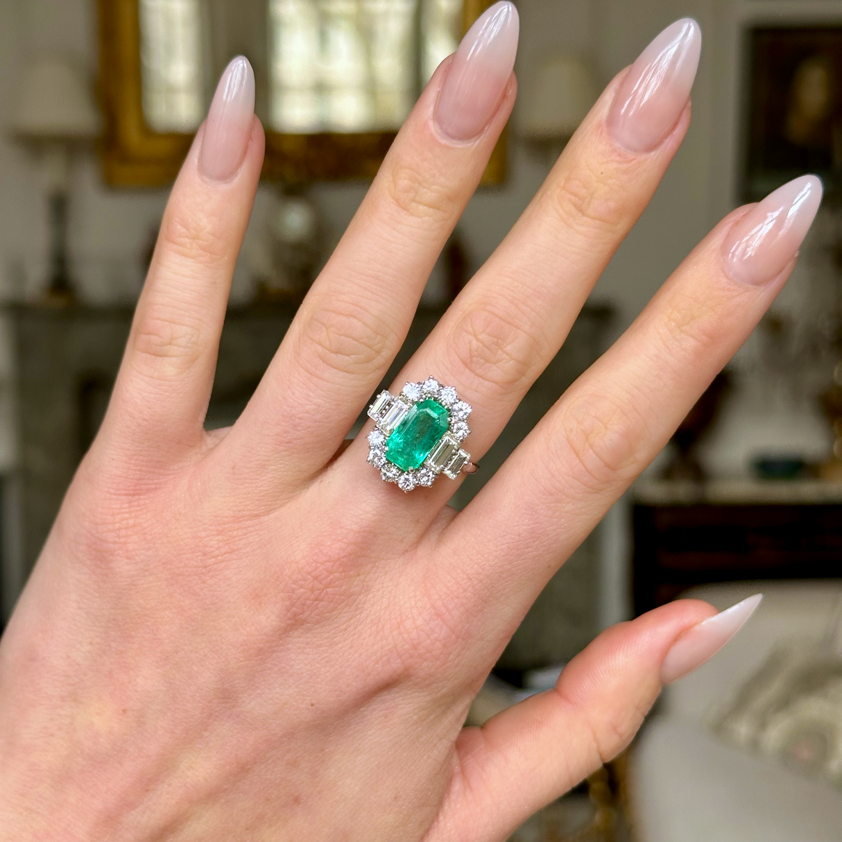Vintage emerald and diamond cluster ring, worn on hand. 