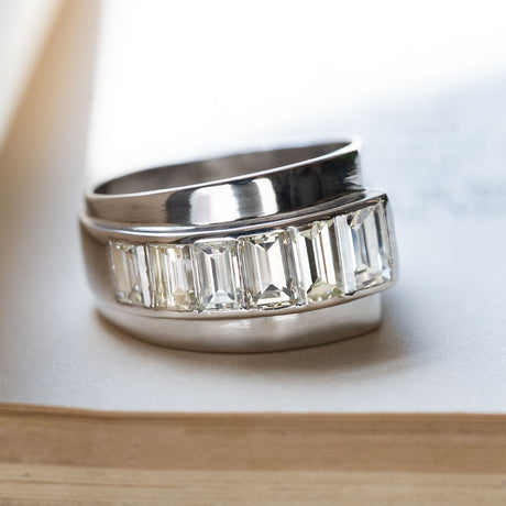 A vintage chunky channel-set baguette-cut diamond ring in platinum displayed on a book.