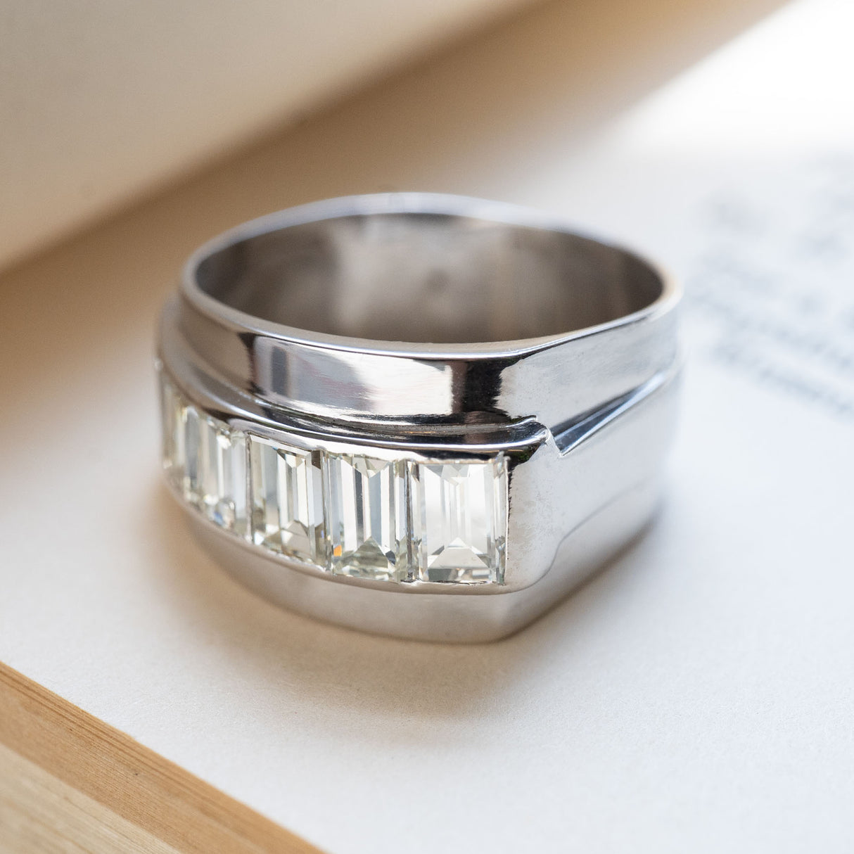 A chunky platinum vintage ring, with channel set baguette cut diamonds on a book. 
