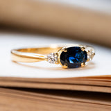A vintage 1960s gold engagement ring with a centre blue sapphire with diamonds on the shoulders. 
