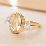 A vintage yellow gold ring with a pale yellow sapphire  at the centre, with two marquise diamonds set in white gold on the shoulders.