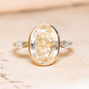 A yellow and white gold vintage ring with a large yellow sapphire flanked by two marquise diamonds.