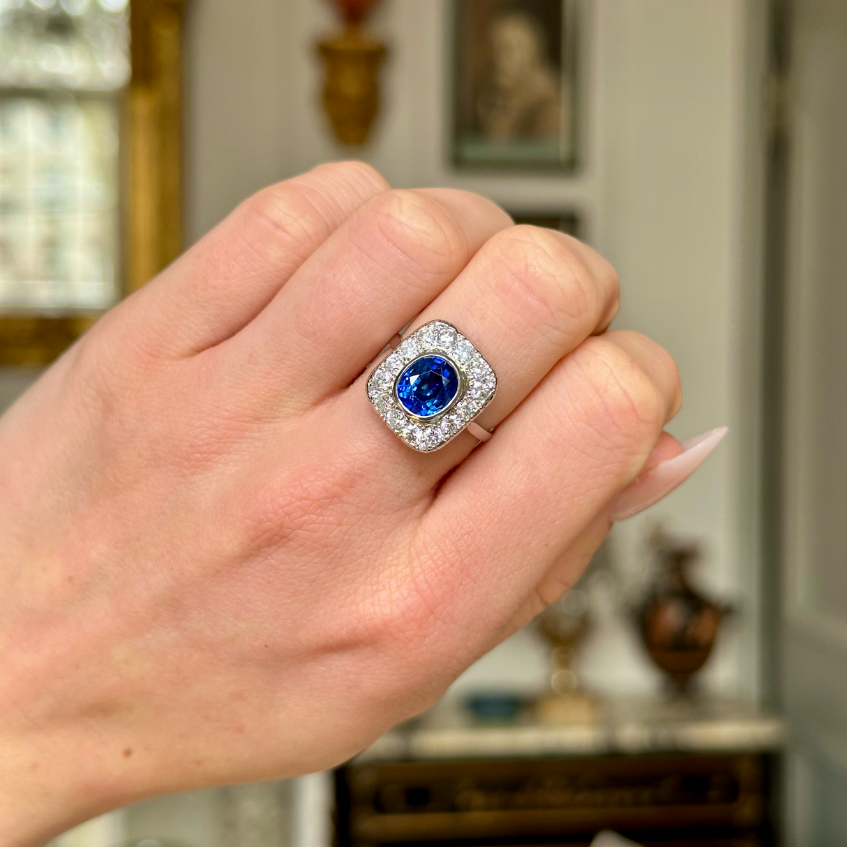 Art Deco sapphire and diamond cluster ring, worn on closed hand. 