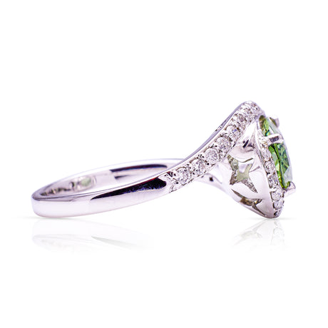 Green sapphire and diamond ring, side perspective on a white background.