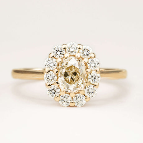 Front view of a yellow-brown tinted old mine-cut diamond cluster engagement ring, showcasing a vintage-inspired design, displayed on a clean off-white background set in yellow gold.