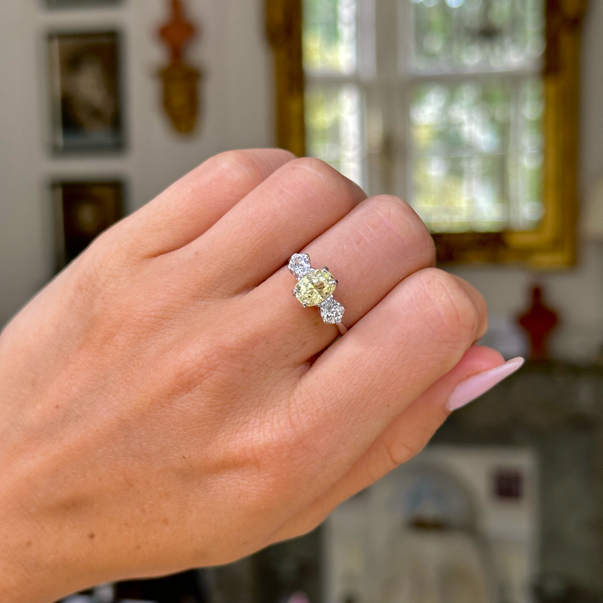 yellow sapphire and diamond three stone engagement ring, worn on closed hand, front view. 