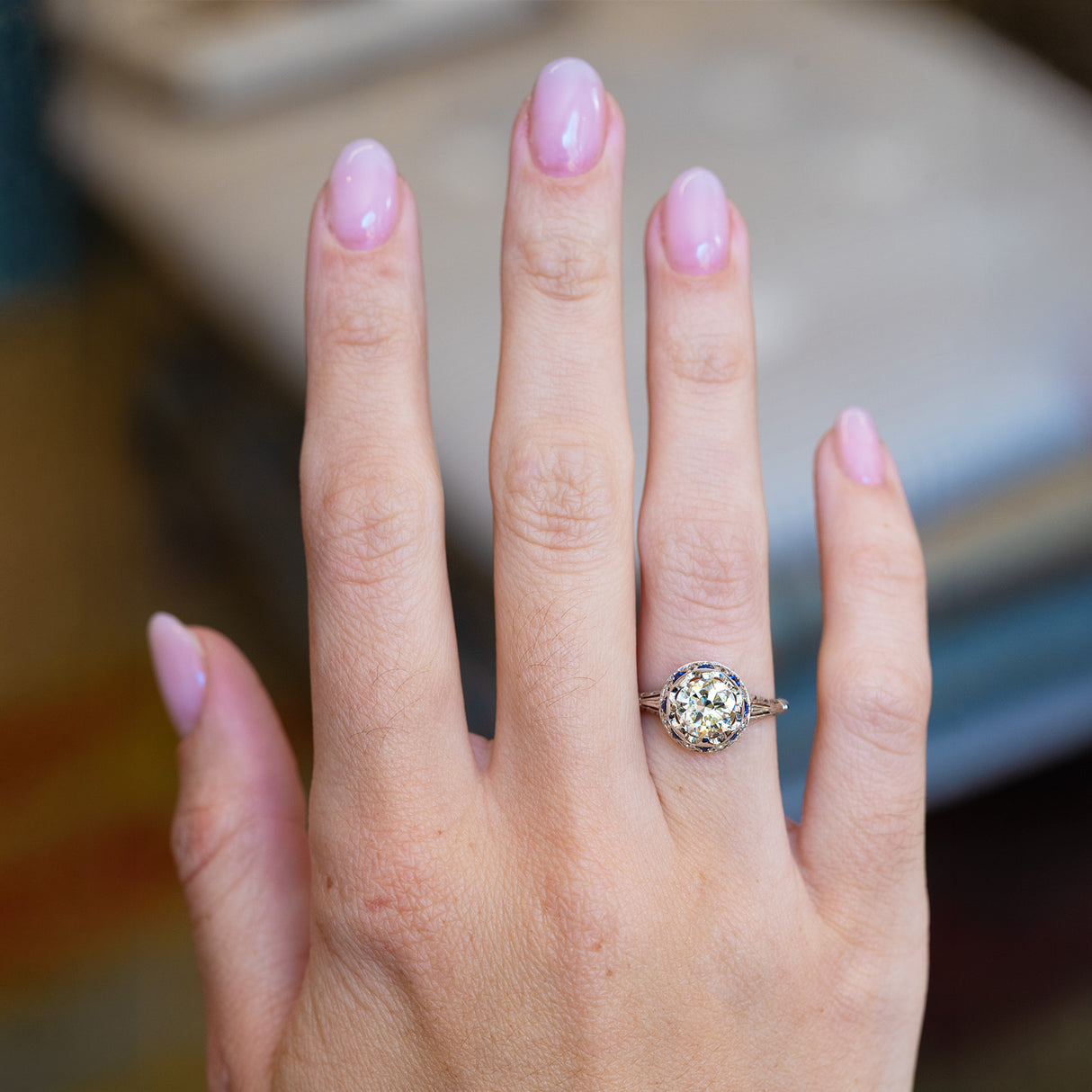 Hand wearing an antique Art Deco diamond and sapphire cluster ring.