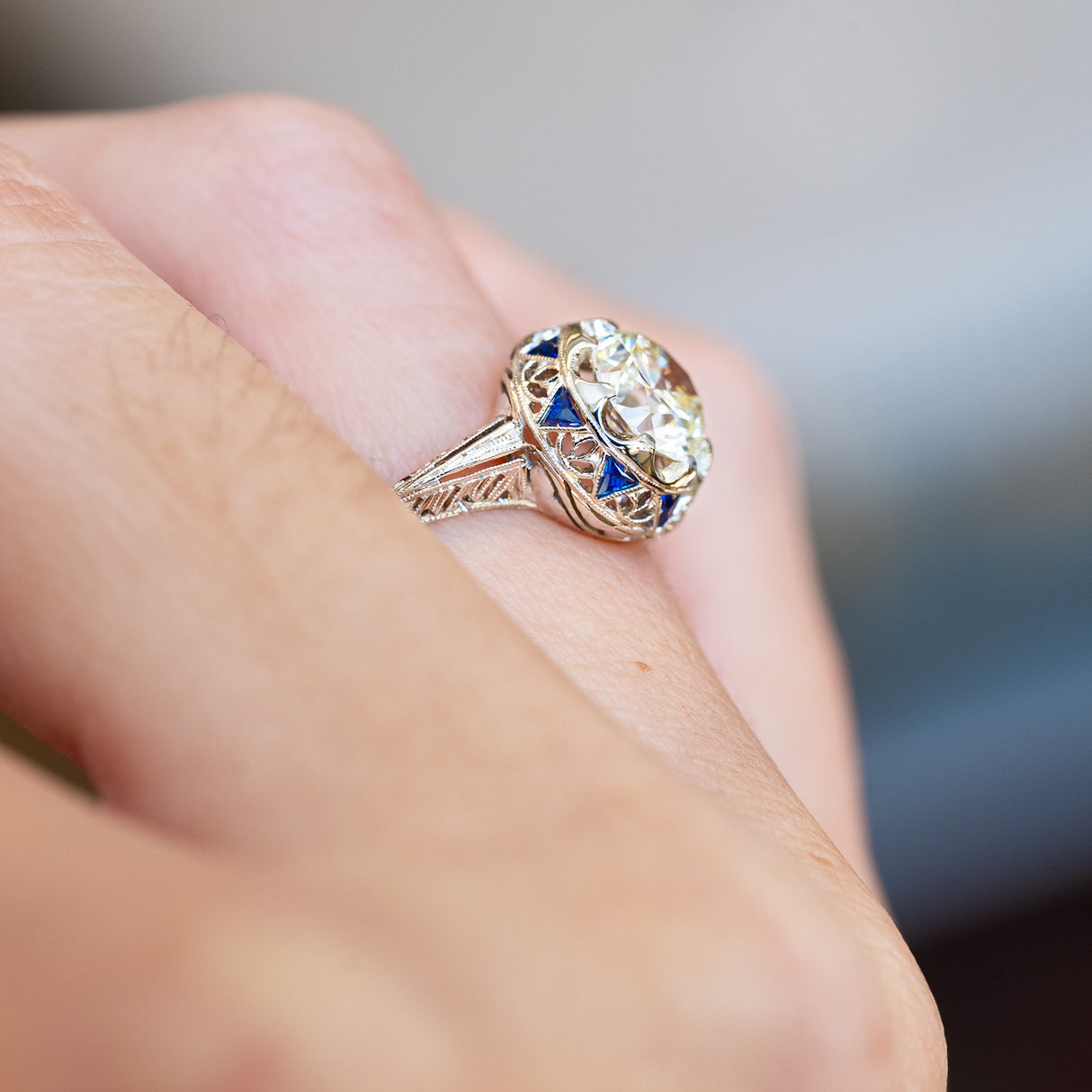 Antique Art Deco diamond and sapphire cluster ring showing side profile with blue sapphire accents.