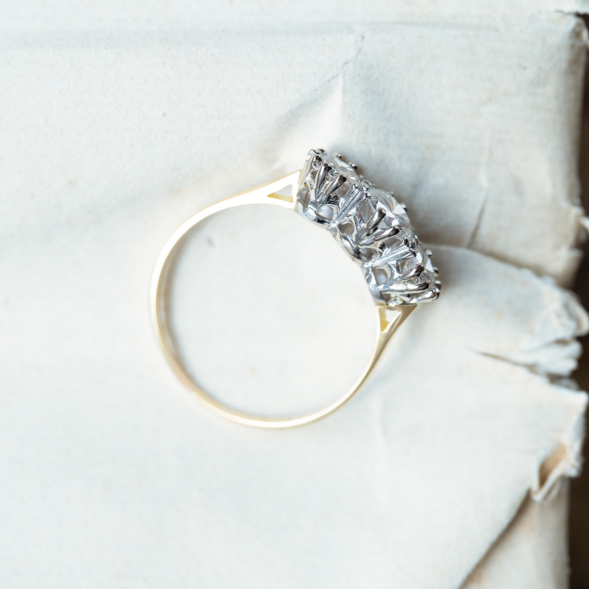 Antique Art Deco diamond three-stone ring with slim yellow gold band and diamond setting.