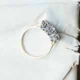 Antique Art Deco diamond three-stone ring with slim yellow gold band and diamond setting.
