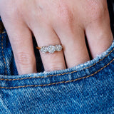 Antique Art Deco diamond three-stone ring worn with hand resting in denim pocket.