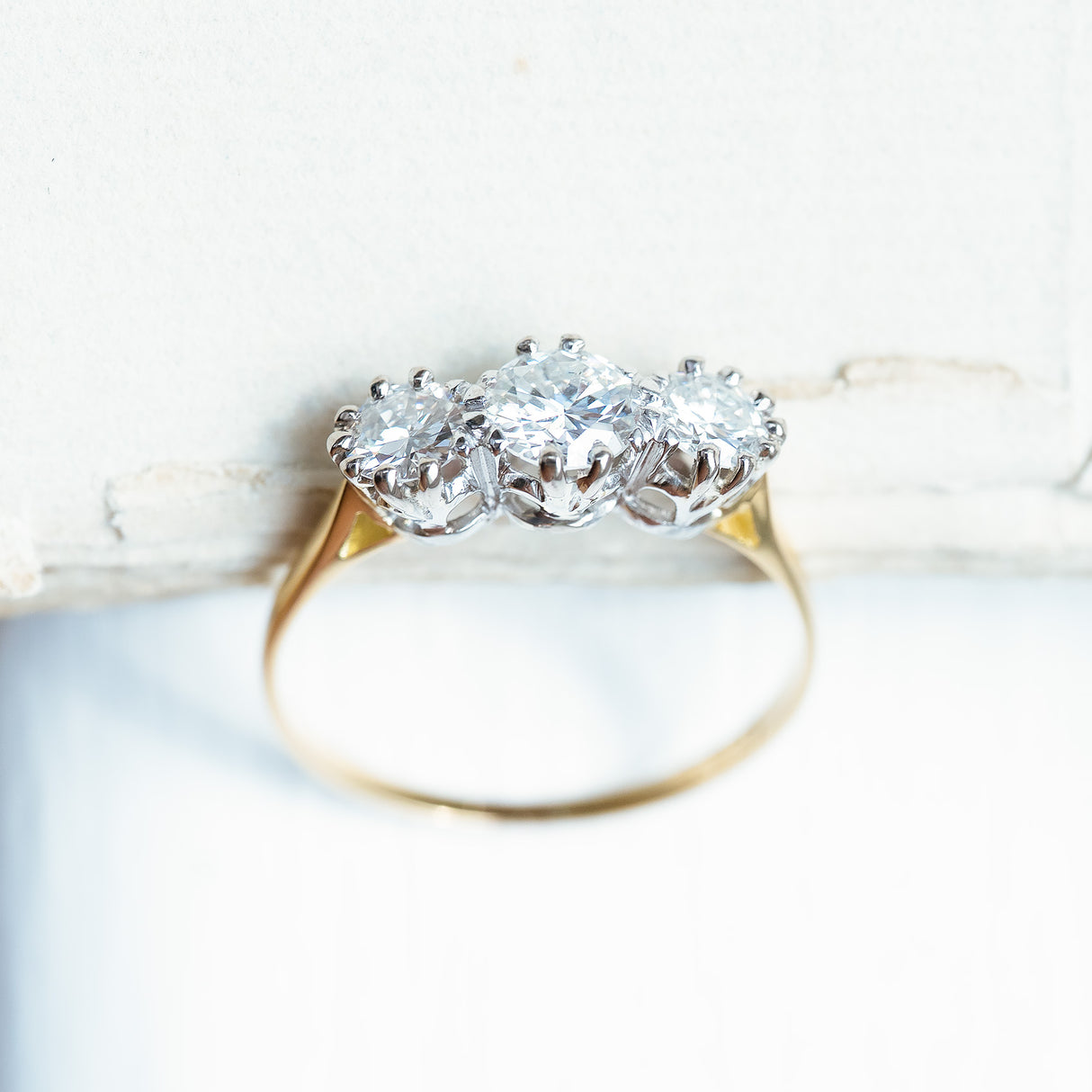 Antique Art Deco diamond three-stone ring showing detailed diamond setting and gold band.