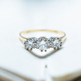 Antique Art Deco diamond three-stone ring resting on open book pages.