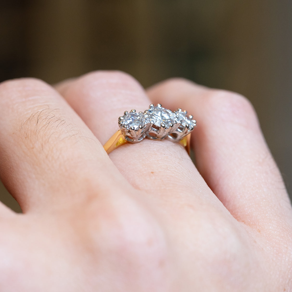 Antique Art Deco diamond three-stone ring with raised diamond setting and delicate gold band.