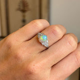 Close-up of an antique Art Deco opal and diamond cluster ring displaying a vibrant opal centre flanked by sparkling diamonds.