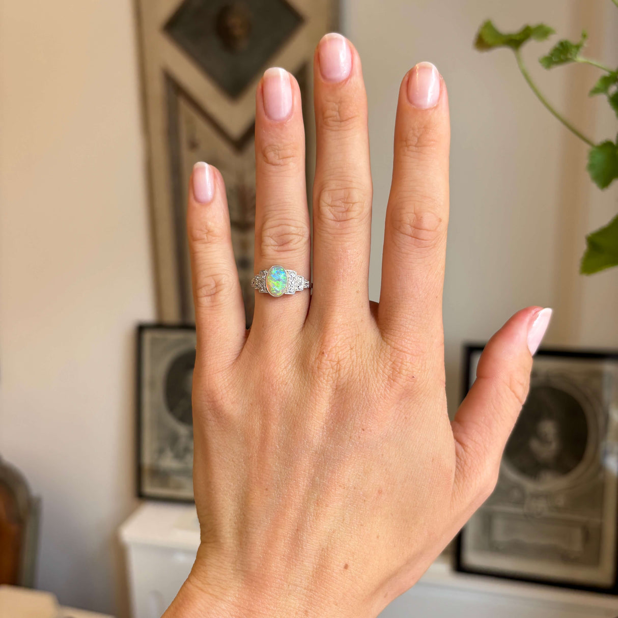 Antique Art Deco opal and diamond cluster ring worn on hand, showcasing a glowing opal centre stone flanked by diamonds on either side.
