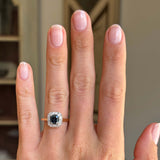 Antique Art Deco sapphire and diamond cluster engagement ring with a blue sapphire centre and diamond cluster surround, displayed on a hand.