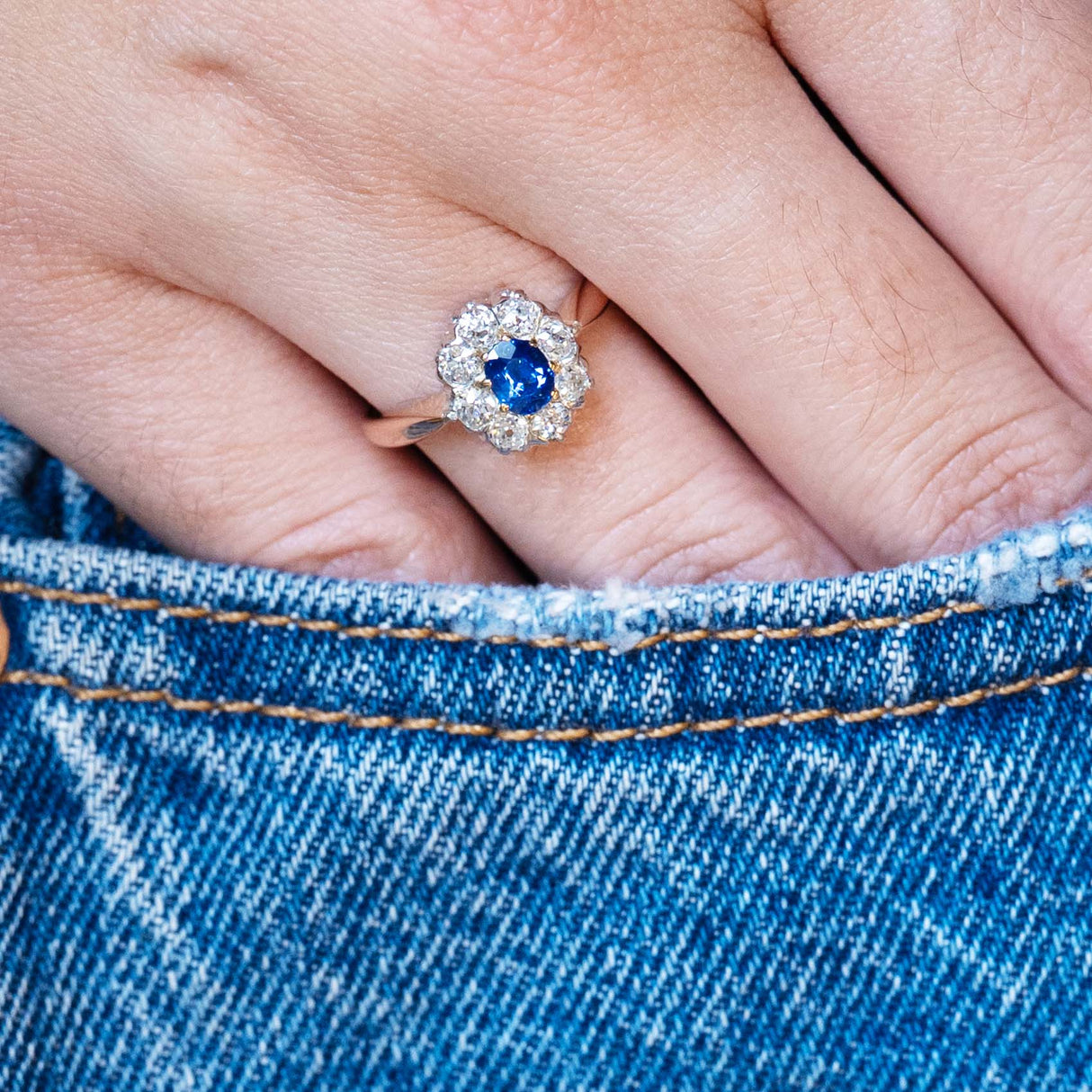 Antique Belle Époque sapphire and diamond cluster engagement ring styled with denim pocket.