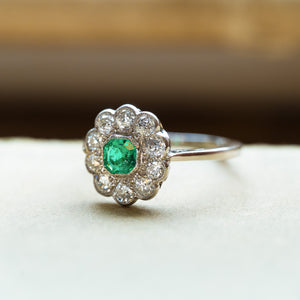 Antique Edwardian emerald and old-mine cut diamond cluster ring with old-mine cut diamond halo surrounding emerald centre stone.
