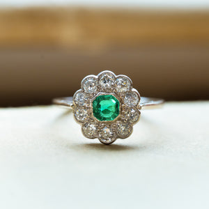Antique Edwardian emerald and old-mine cut diamond cluster ring with scalloped diamond cluster and vivid green emerald.