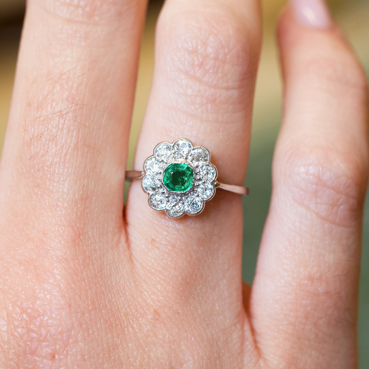 Antique Edwardian emerald and old-mine cut diamond cluster ring with vivid green emerald centre stone and diamond halo.