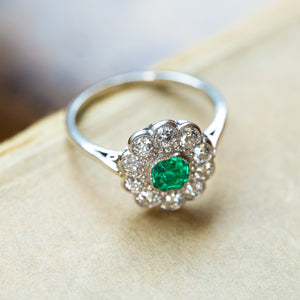 Antique Edwardian emerald and old-mine cut diamond cluster ring with fine detailing along the band and floral diamond cluster.