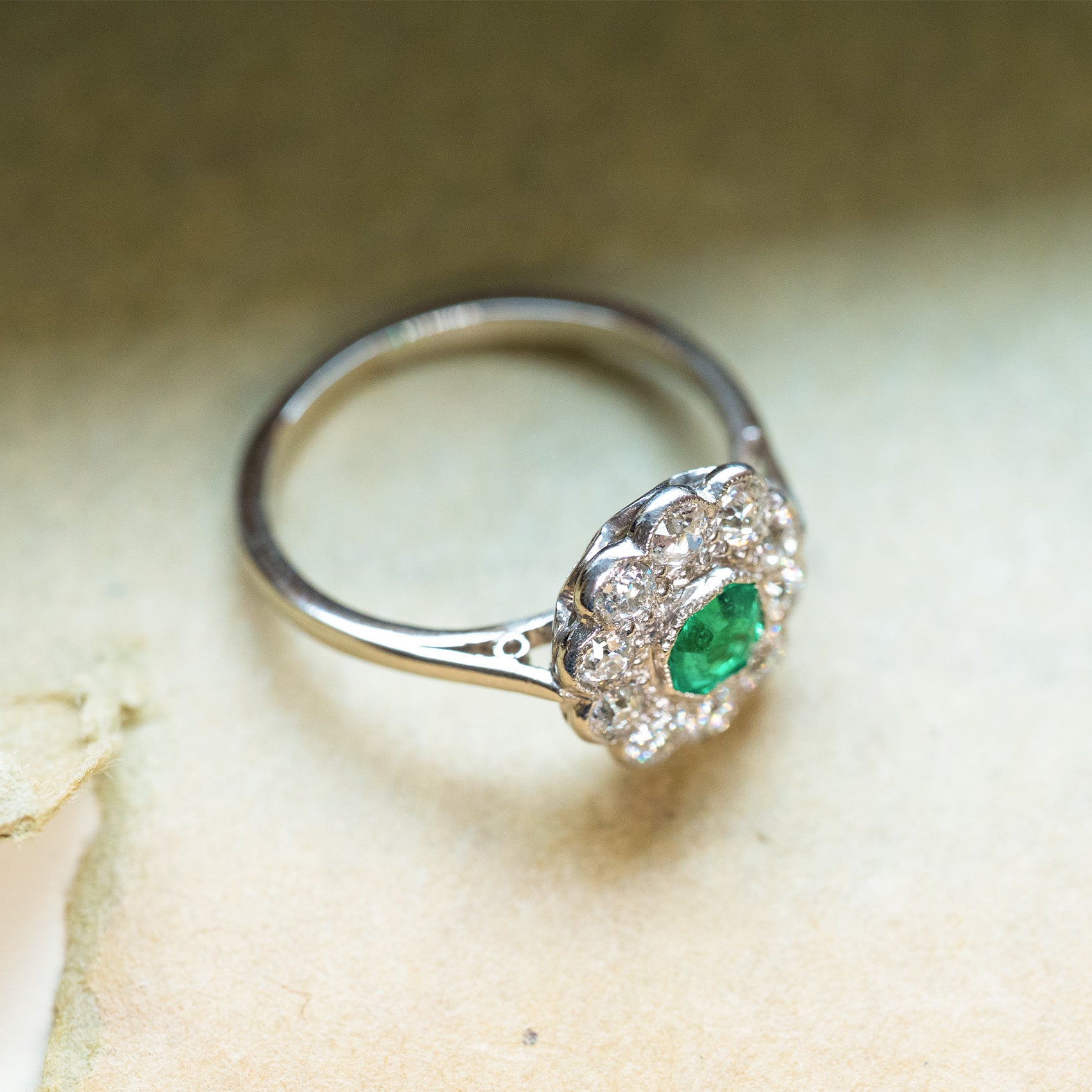 Antique Edwardian emerald and old-mine cut diamond cluster ring with floral cluster design and bright green emerald centre.