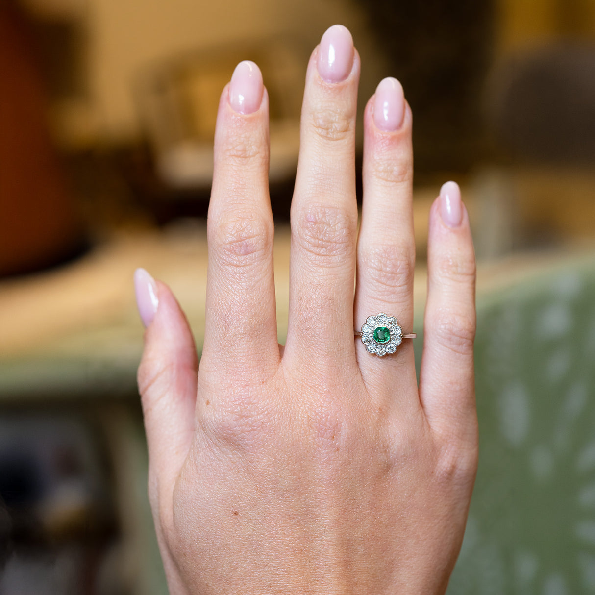 Antique Edwardian emerald and old-mine cut diamond cluster ring worn on hand.