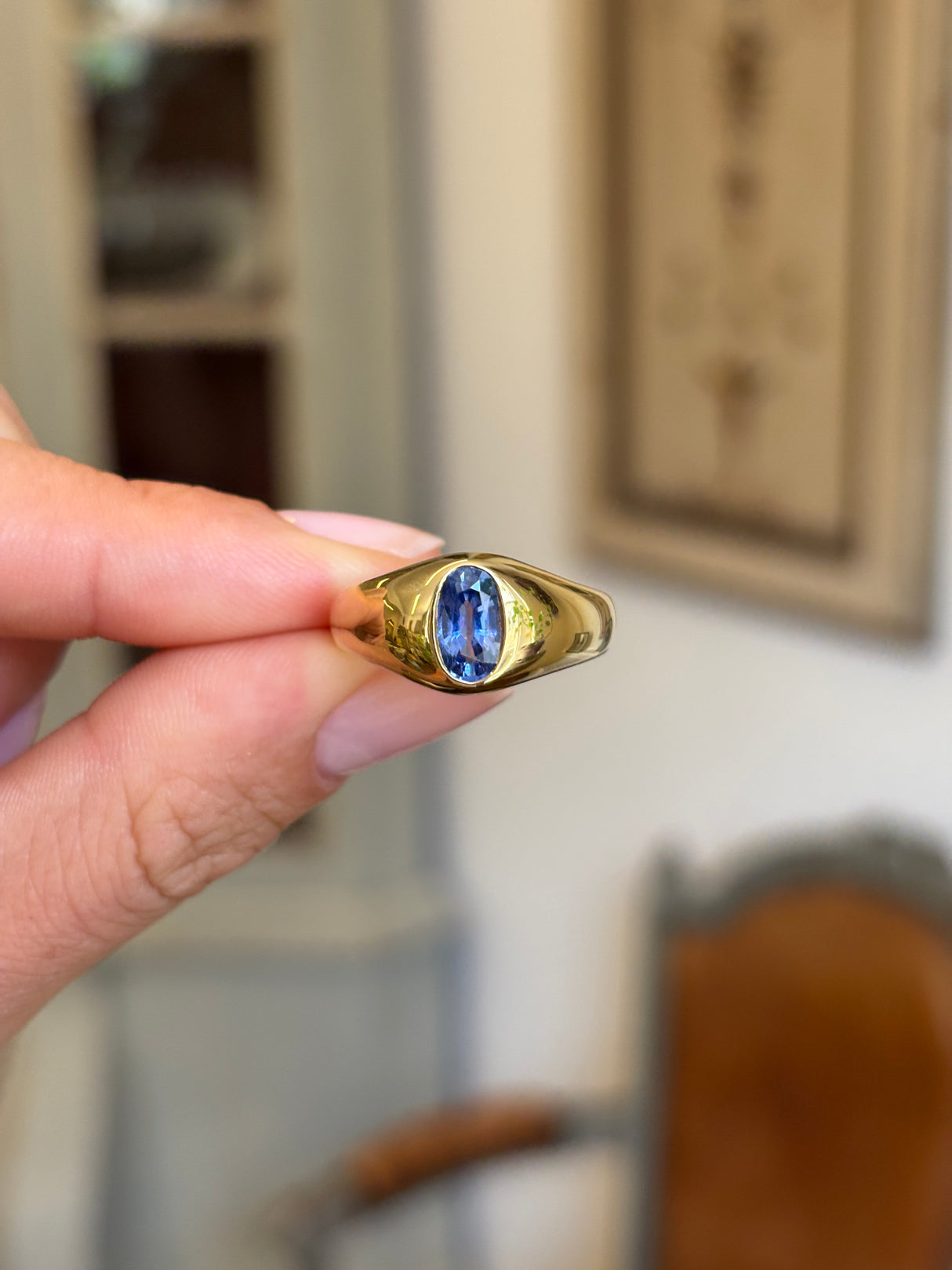 Antique Edwardian iris-blue sapphire gypsy engagement ring featuring an iris-blue sapphire set in a classic gypsy setting, held by hand.