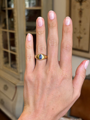 Antique Edwardian iris-blue sapphire gypsy engagement ring with an iris-blue sapphire centre stone in a traditional gypsy setting, displayed on a hand.