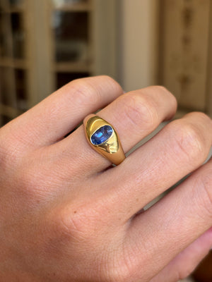 Antique Edwardian iris-blue sapphire gypsy engagement ring featuring an iris-blue sapphire in a classic gold gypsy setting, worn on a hand.
