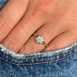 Antique Edwardian old-cut diamond daisy cluster ring photographed on hand against denim, highlighting the floral diamond cluster design and antique craftsmanship.