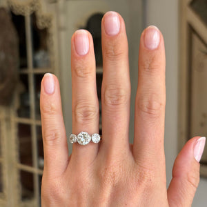 Antique Edwardian old-cut diamond three-stone engagement ring with three old-cut diamonds, displayed on a hand.